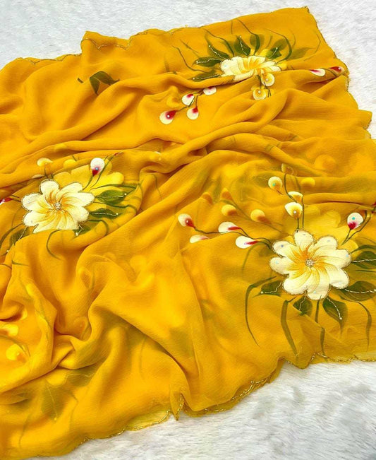A yellow scarf with hand-painted floral designs in white, yellow, and green, draped on a white textured surface.