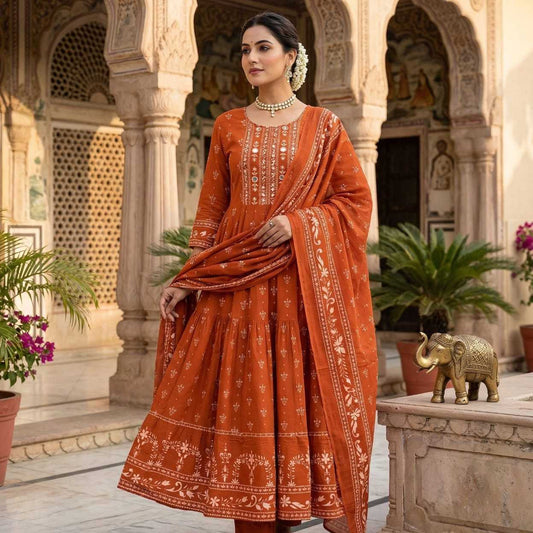 Woman in traditional orange outfit standing in an ornate architectural setting.
