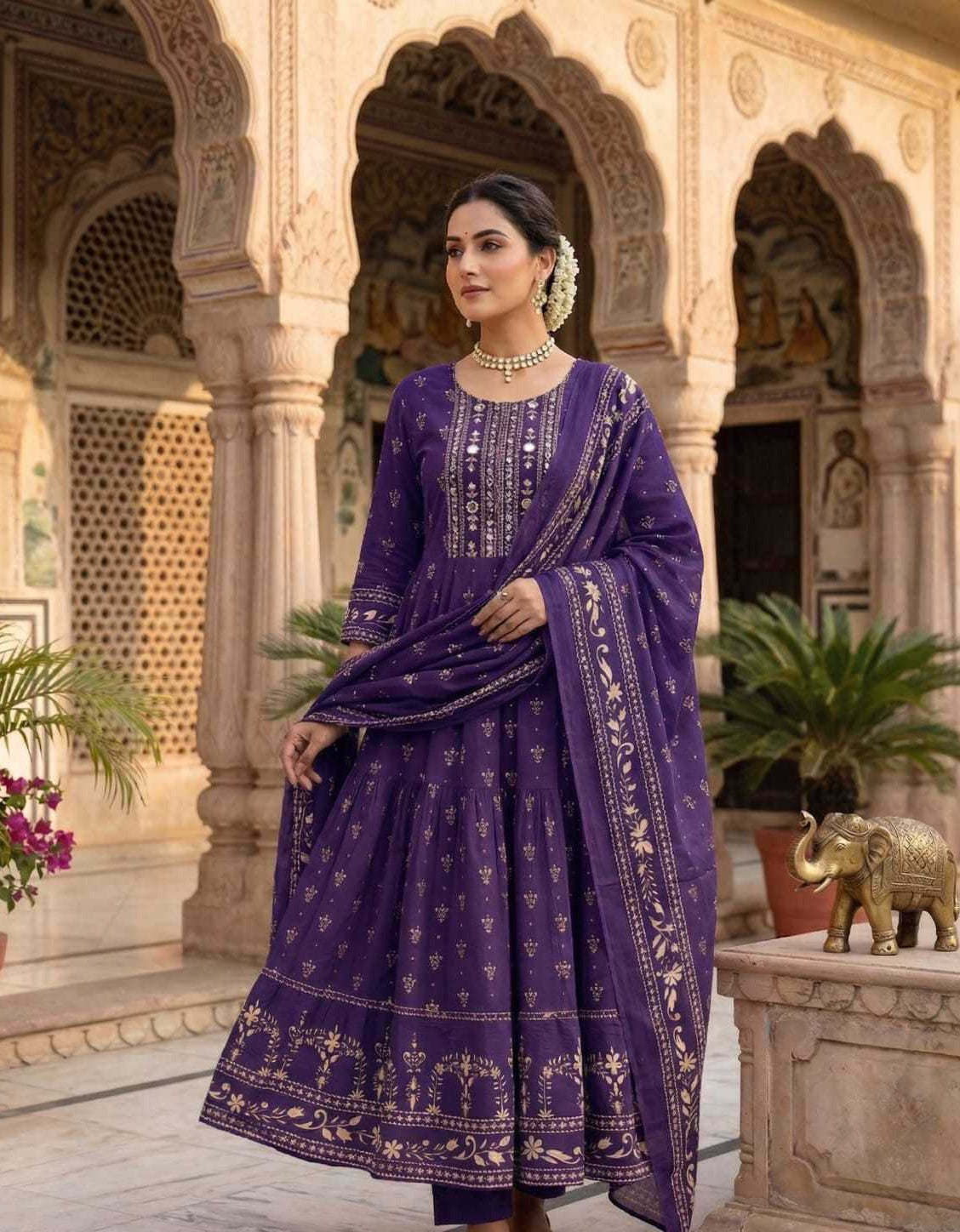 Woman in a purple traditional outfit standing in an ornate architectural setting.