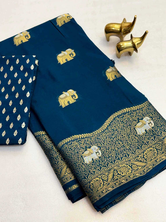 A folded navy blue fabric garment, likely a sari or dress material, featuring gold elephant motifs and an ornate gold border, with a matching patterned fabric piece folded over on the left. Two small gold elephant figurines are placed on a light background.