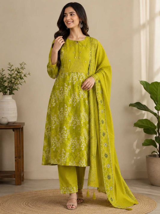 Woman wearing a green traditional outfit with a dupatta in a home setting