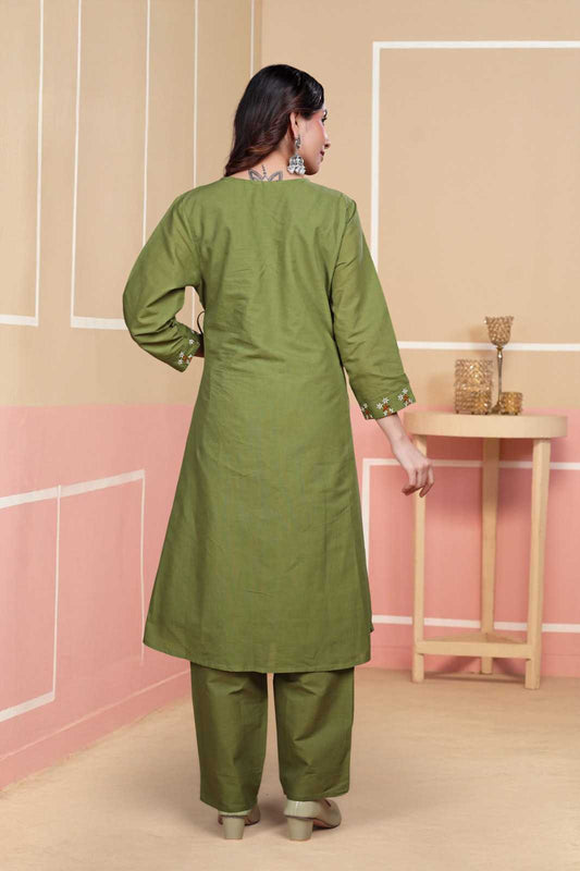 Woman wearing a green kurta with pants in a minimalistic room.