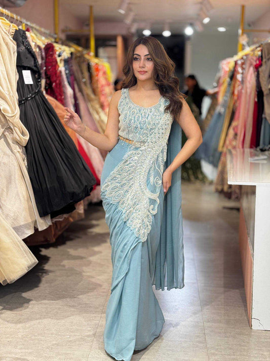 Woman in a light blue saree with white embroidery in a clothing store.