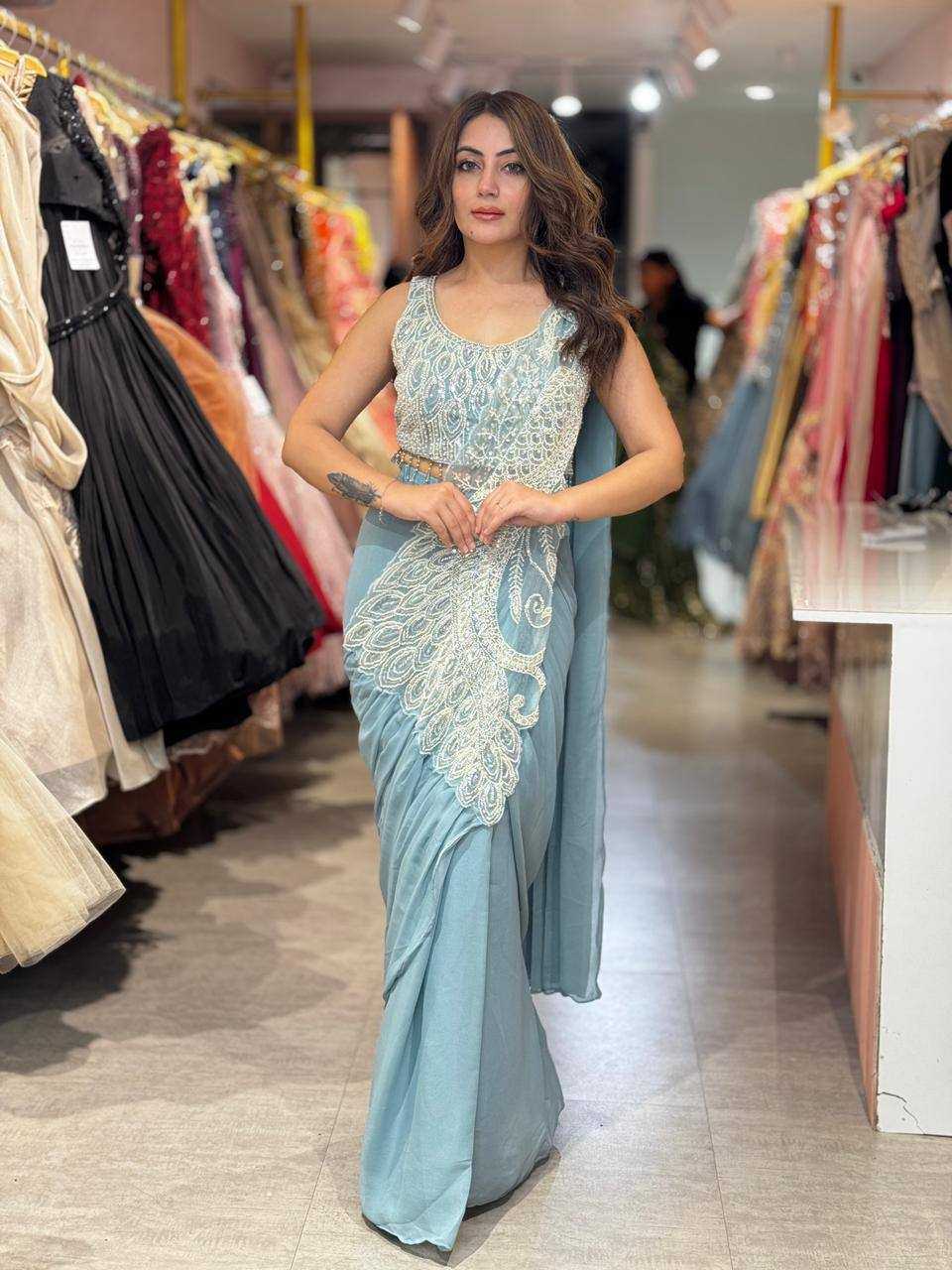 Woman in a light blue saree with white embroidery standing in a clothing store.
