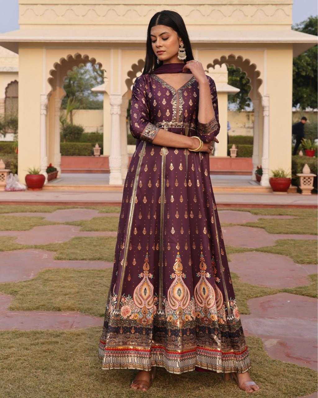 Woman in a traditional outfit standing in front of an architectural structure with greenery.