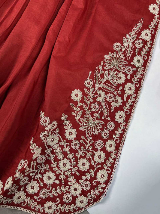 Red fabric with intricate white floral embroidery on a white background
