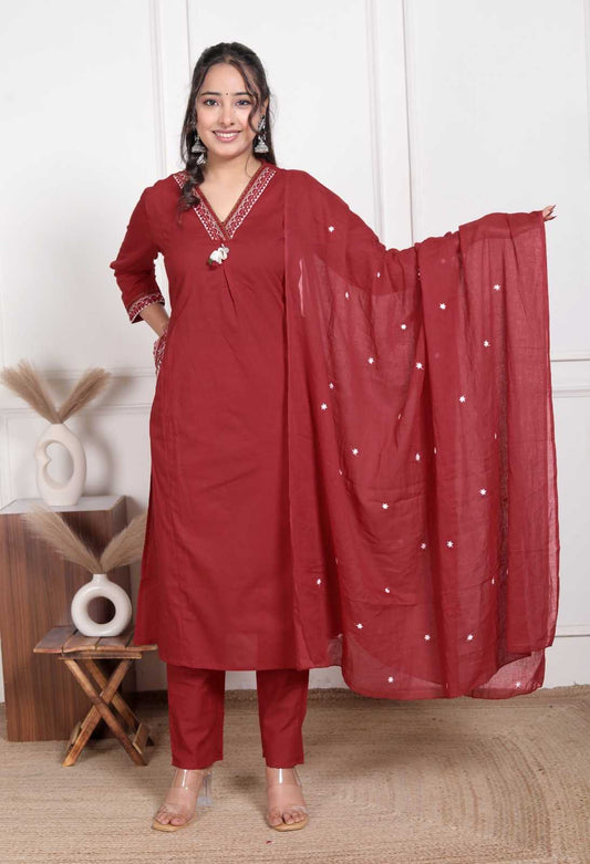 Woman wearing a red traditional outfit with a matching dupatta in a minimal indoor setting.