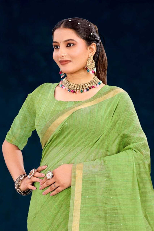 Woman wearing a green saree with gold border against a dark background