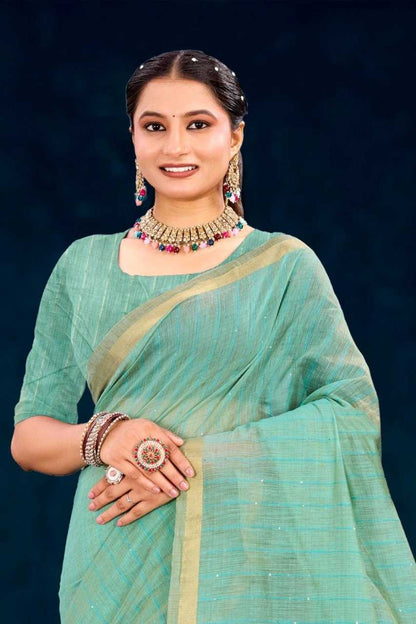 Woman wearing a light blue saree with gold border against a dark background
