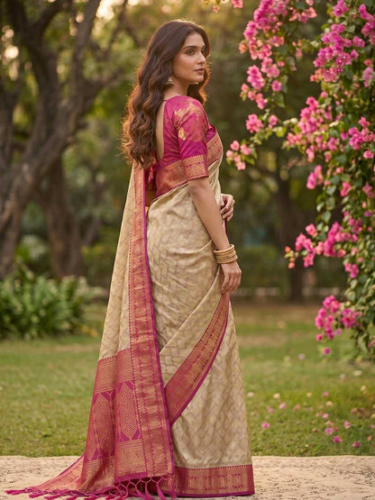 Woman in a traditional saree standing in a garden with pink flowers and greenery.