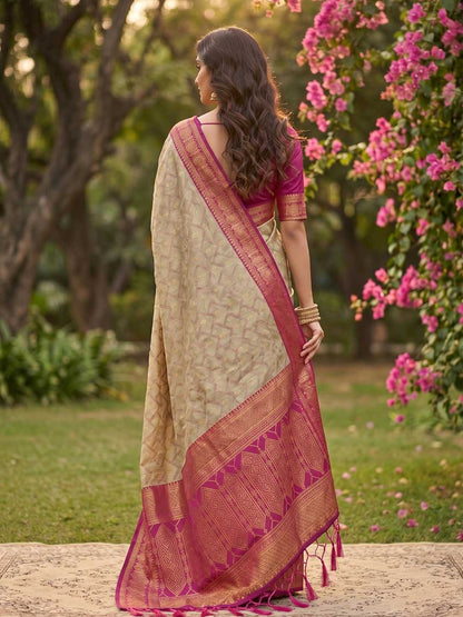 Woman in a traditional saree standing in a garden with pink flowers and greenery.