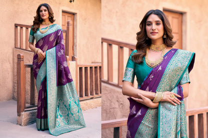 Woman wearing a purple and teal saree with jewelry, standing in front of a beige wall.