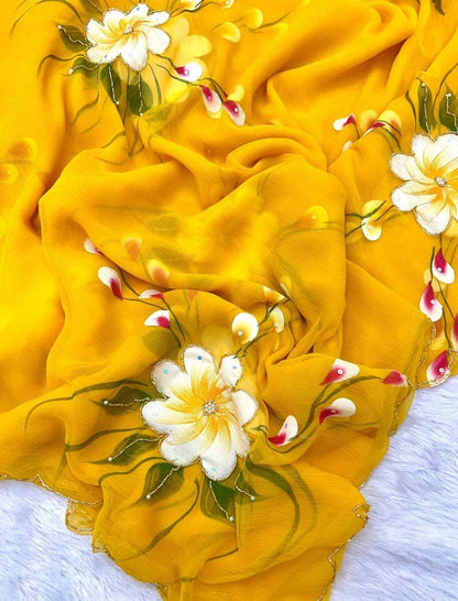A yellow scarf or fabric piece with hand-painted white flowers, green leaves, and small red accents, draped on a white textured surface.