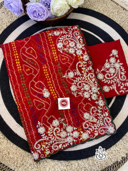 Red embroidered fabric with white patterns on a circular mat with flowers in the background