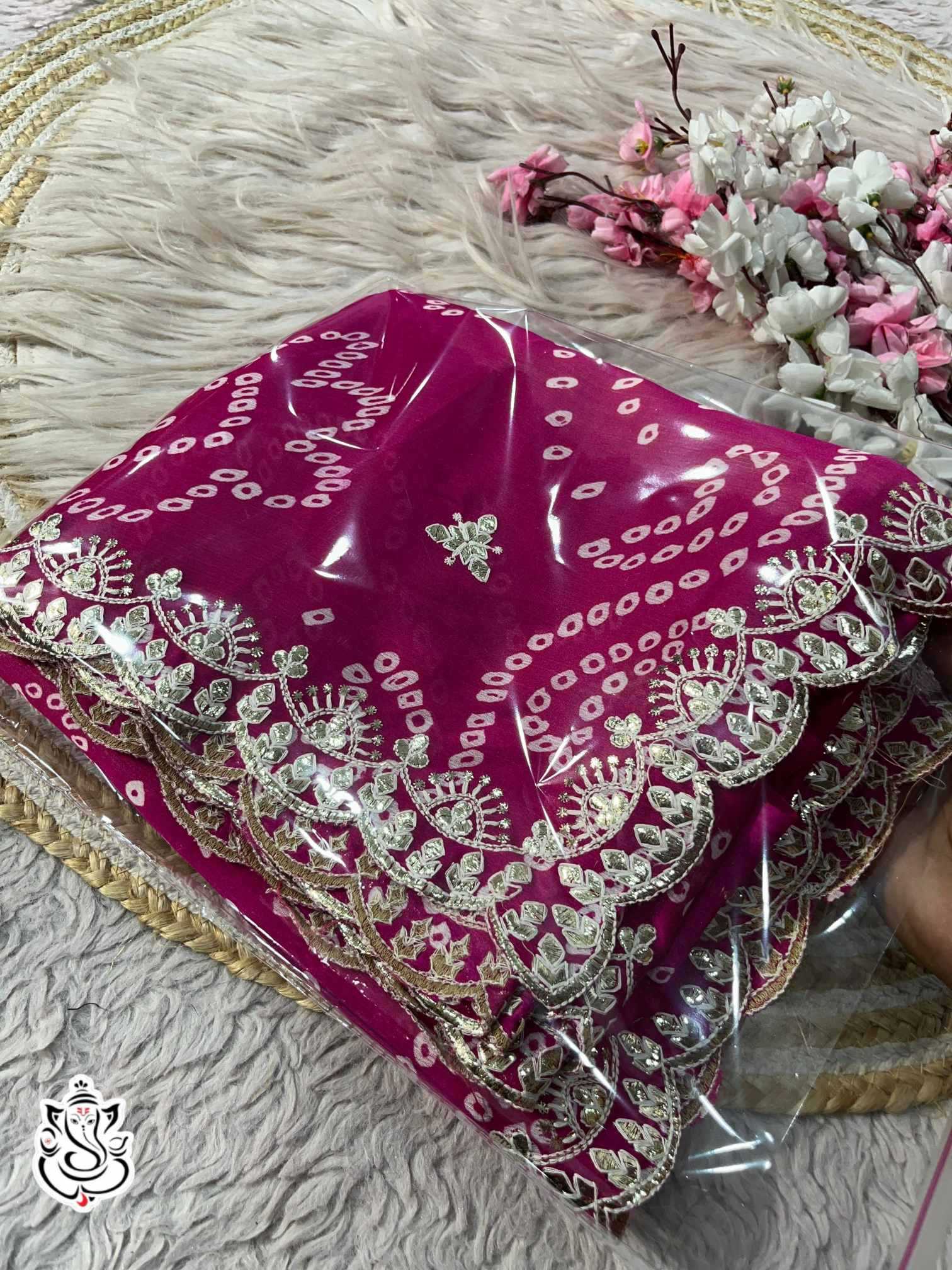 Decorative pink fabric with gold embroidery on a textured surface.