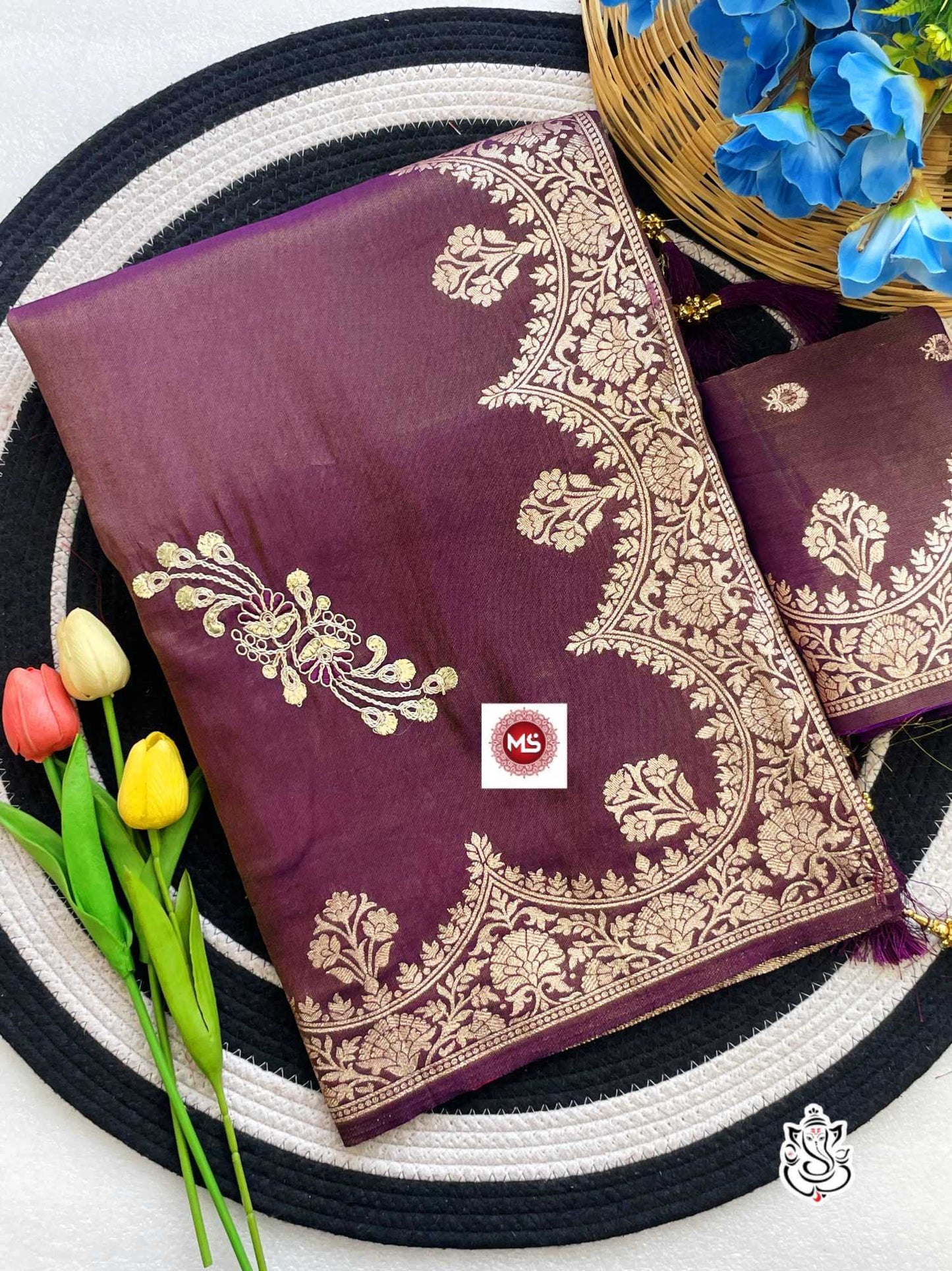 Purple saree with gold embroidery on a woven mat with tulips and flowers.