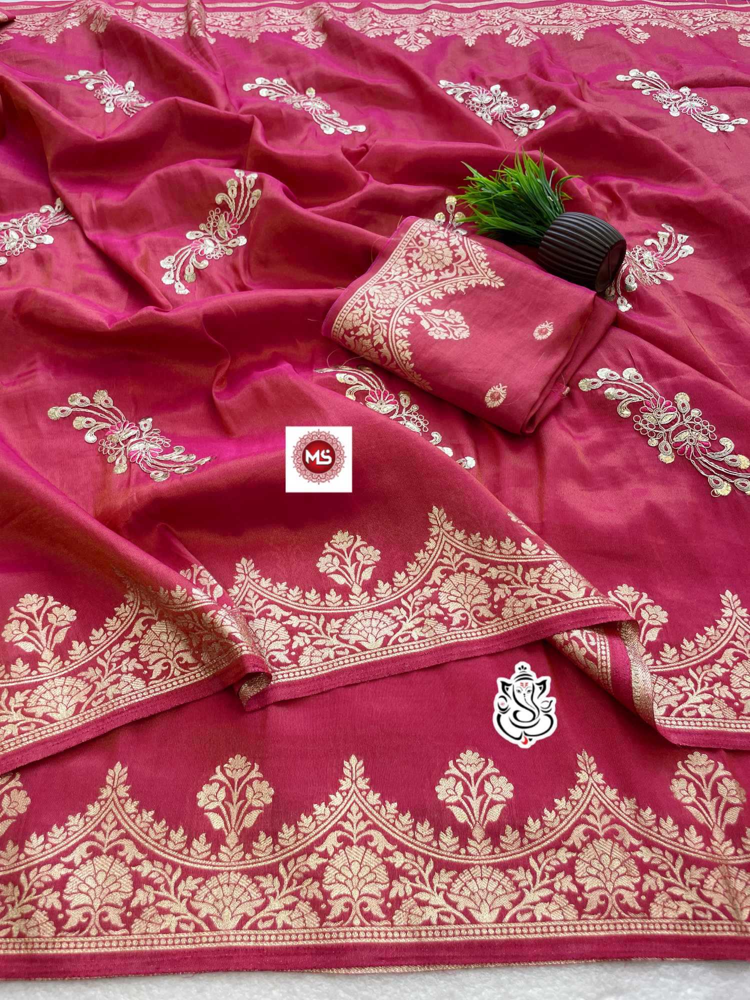 Pink saree with white embroidery and a brand logo in the center.