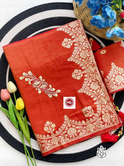 Red saree with white embroidery on a black and white striped background with flowers.