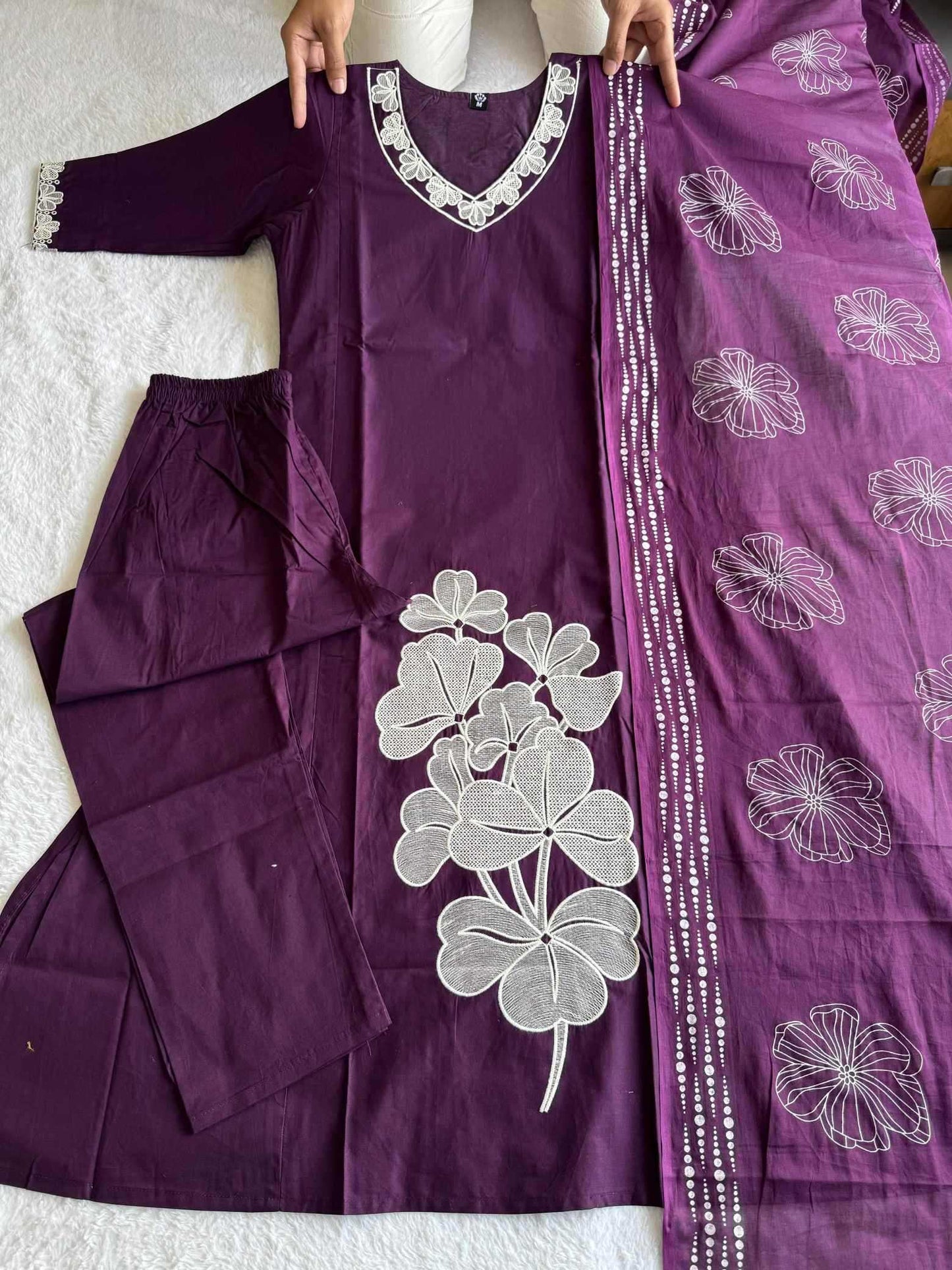 Purple outfit with white floral embroidery on a textured surface