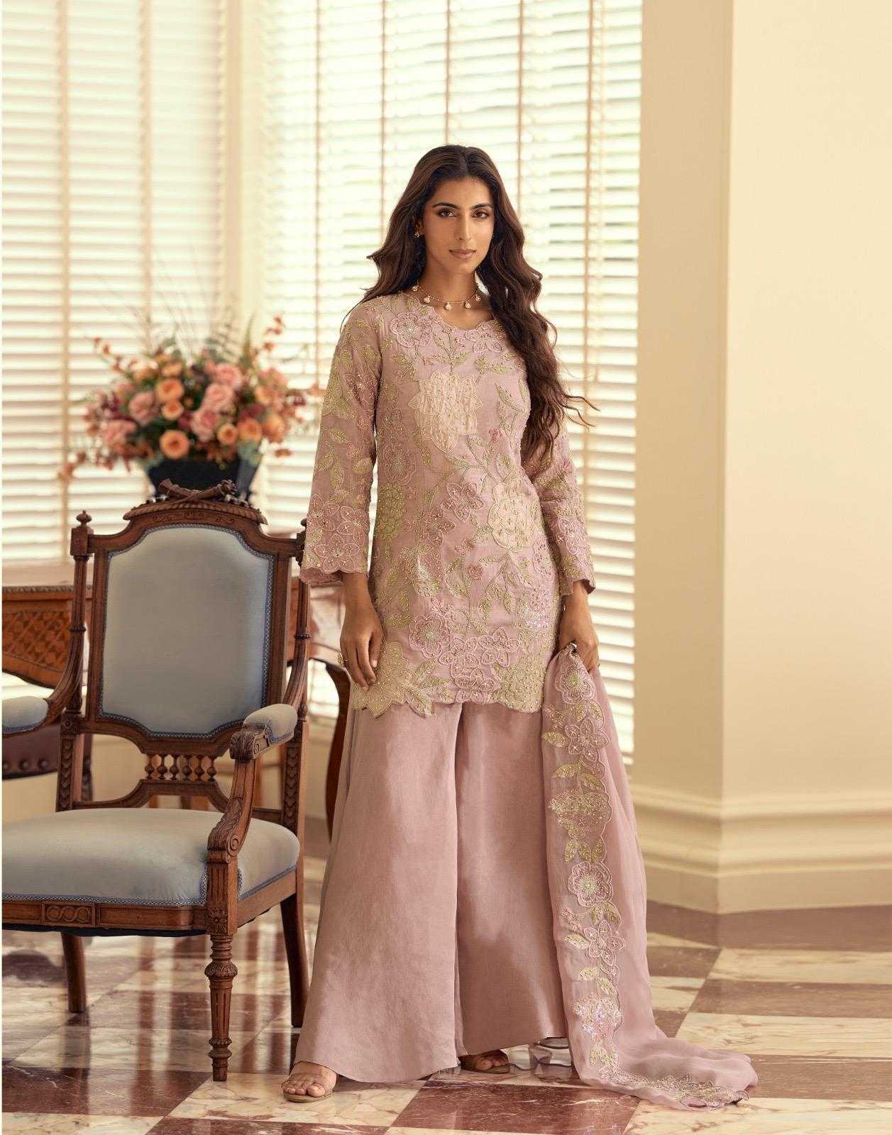 Woman in a traditional outfit standing in a room with a chair and flowers.