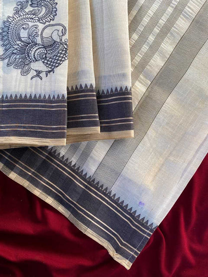 A close-up of a folded white and light gray striped fabric with dark navy borders, a printed peacock motif on the left, and a deep red satin-like fabric underneath.