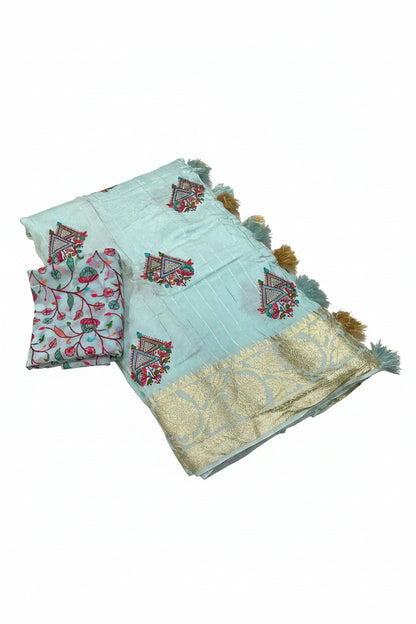 A folded light sky blue georgette sari with Kashmiri style embroidery, featuring geometric and floral motifs in red, green, and gold, with a wide gold zari border and tassel trim. A matching folded fabric piece is placed beside it on a white background, with text detailing the fabric specifications.