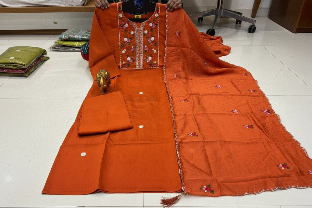 Orange embroidered traditional outfit on a white floor
