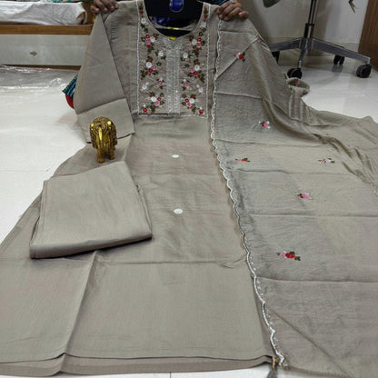 Gray traditional outfit with floral embroidery on a white floor.