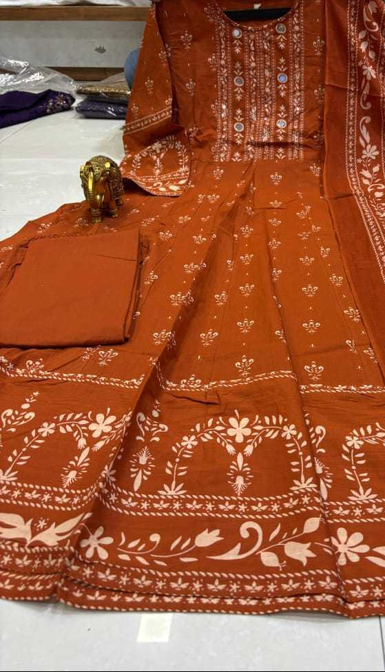 Orange traditional outfit with white patterns on a white floor.