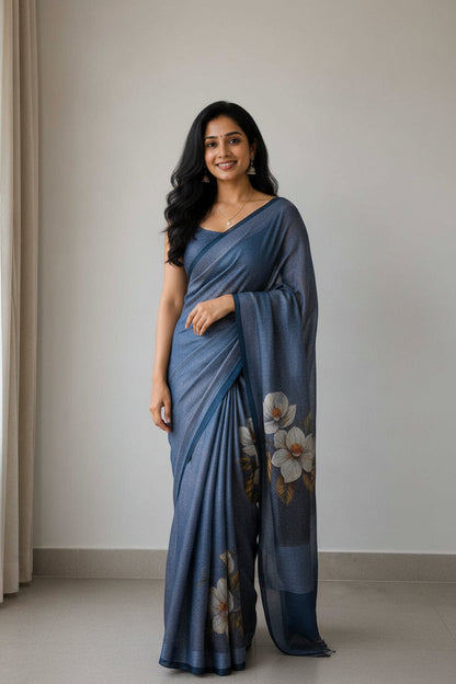 Woman wearing a blue saree with floral patterns, taking a mirror selfie.
