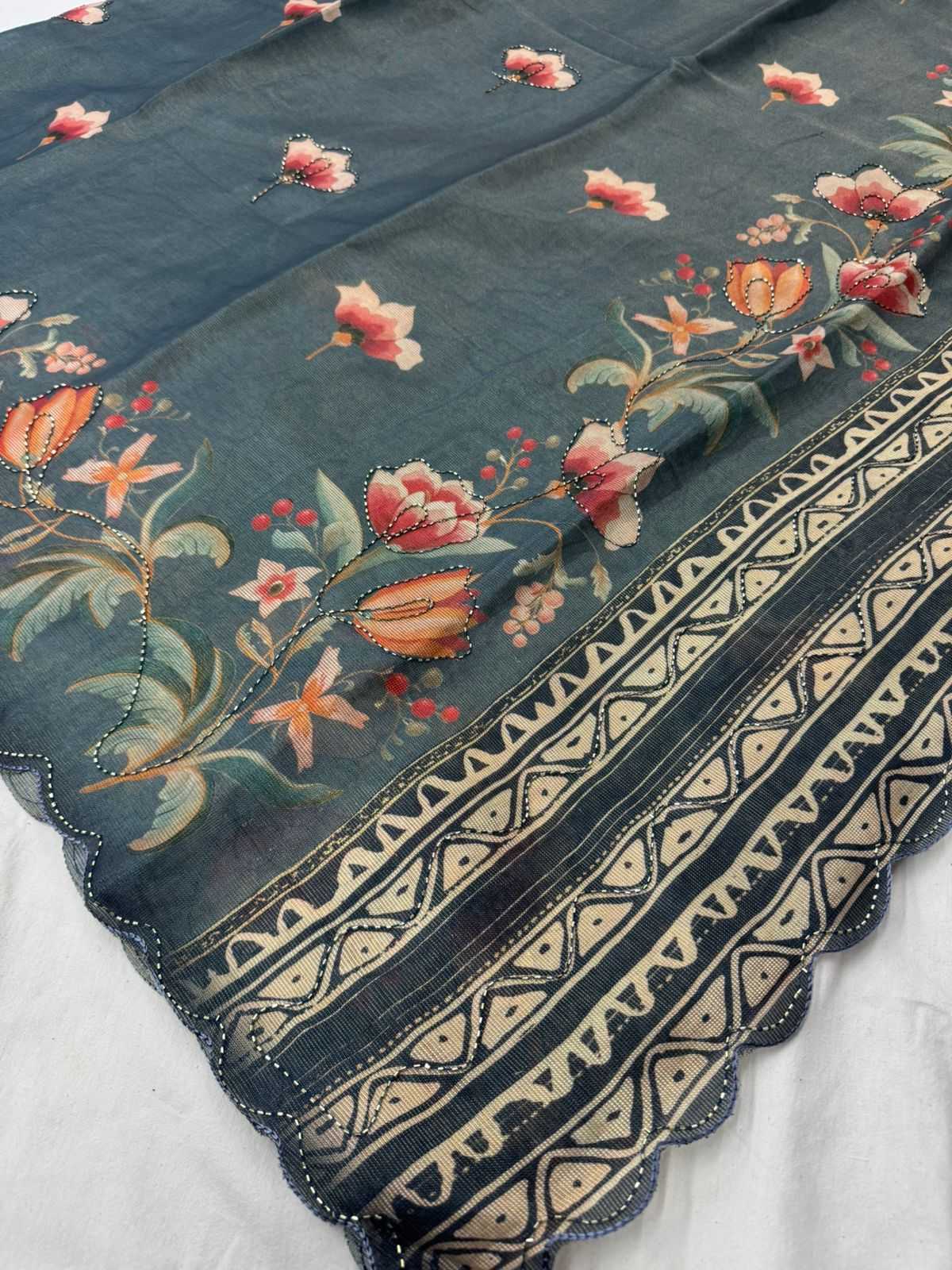 Embroidered fabric with floral patterns and geometric designs on a dark blue background.