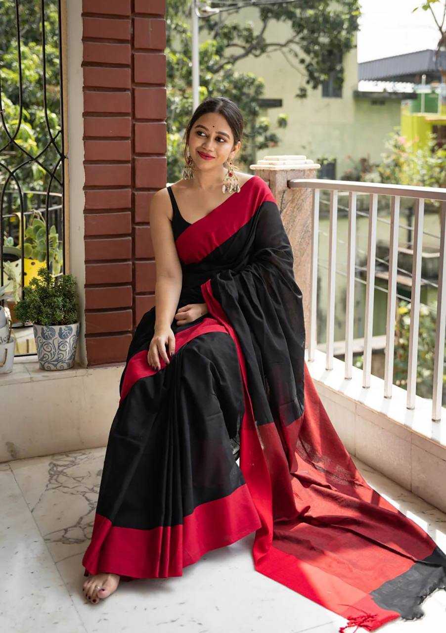 Woman in a black and red saree sitting on a balcony.