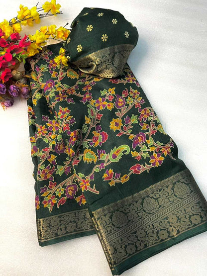 A dark green floral printed fabric set with a matching head covering, laid flat on a white background with decorative yellow and red flowers in the top left corner. The fabric features a multicolor floral pattern with yellow, pink, and green blossoms on a dark green base, finished with a wide metallic gold brocade border.