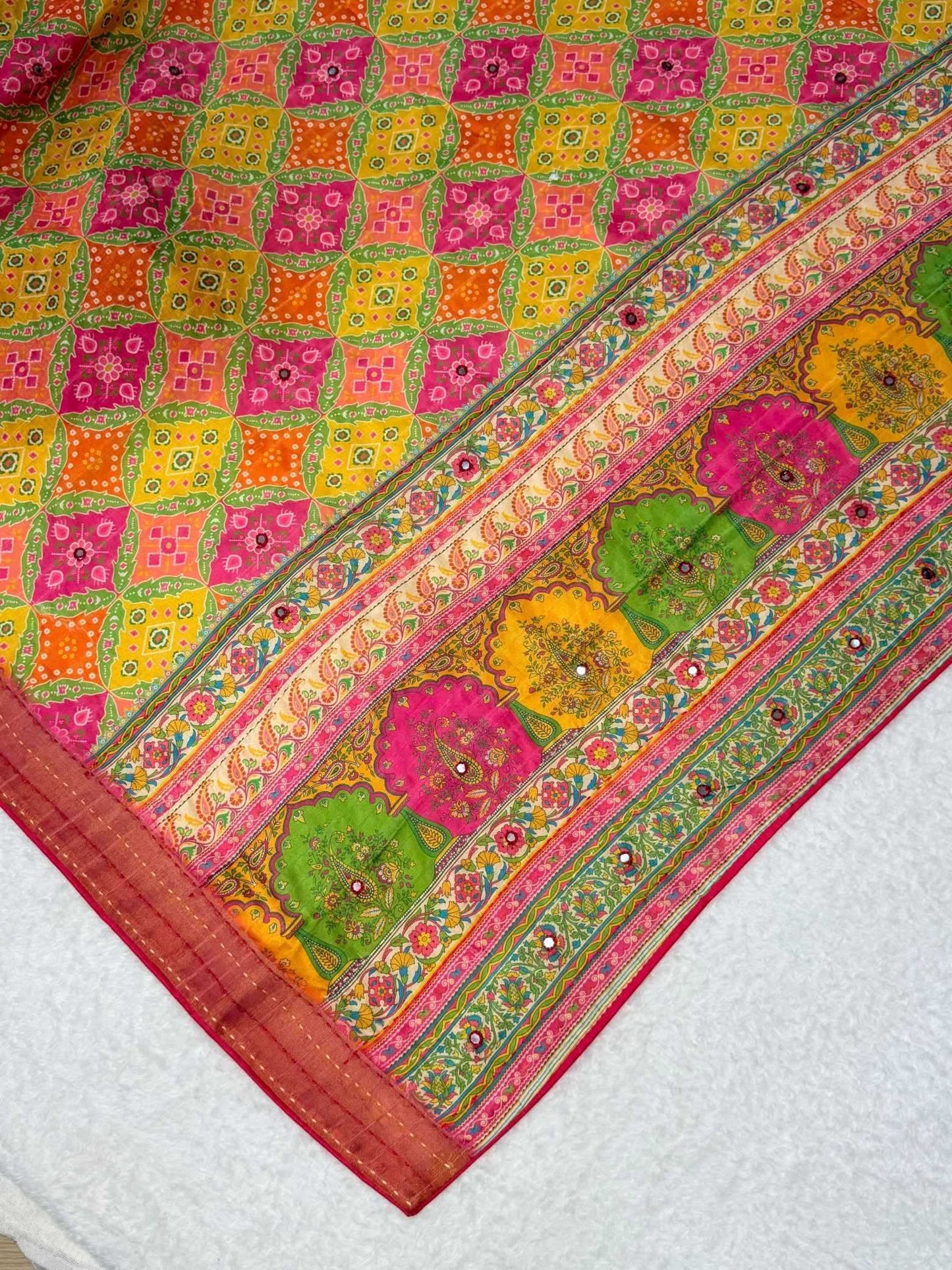 Colorful patterned fabric with a mix of pink, green, yellow, and orange on a white background