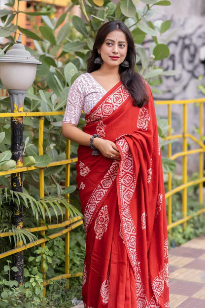 Woman wearing a red saree with white patterns in an outdoor setting