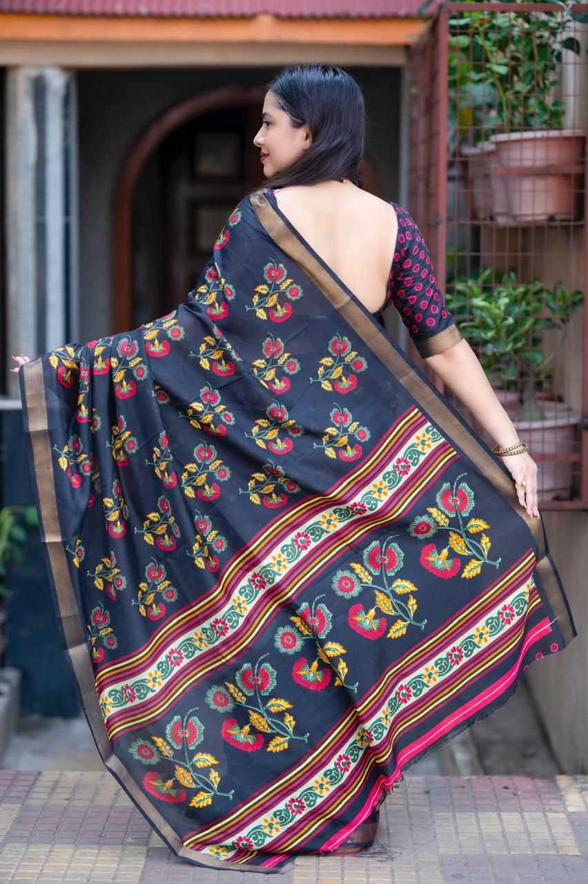 Woman wearing a dark blue saree with colorful patterns in an outdoor setting.