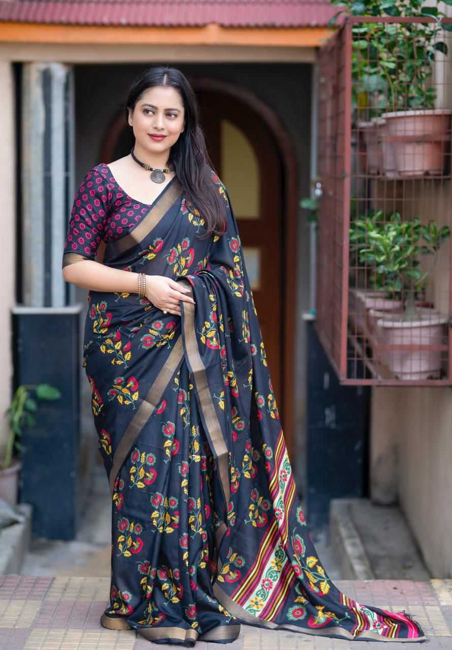 Woman wearing a dark blue saree with floral patterns standing in front of a door.