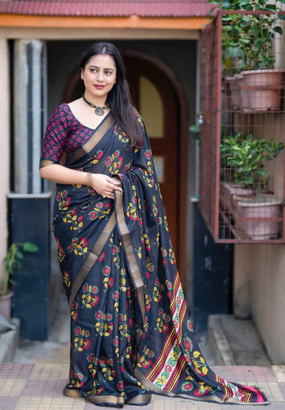 Woman wearing a dark blue saree with floral patterns standing in front of a door.
