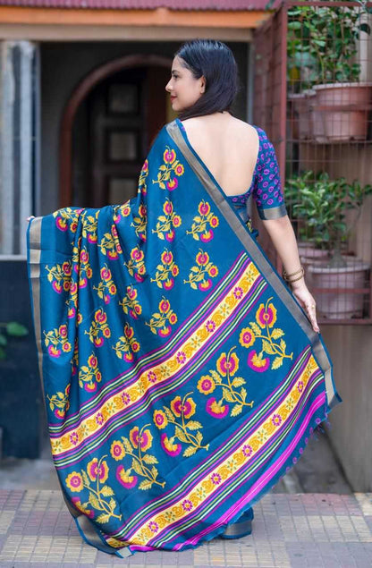 Woman wearing a blue saree with floral patterns in an outdoor setting