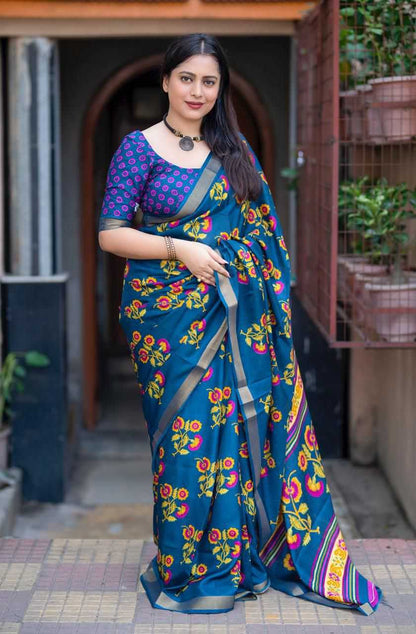 Woman wearing a blue floral saree with a traditional blouse in an outdoor setting.