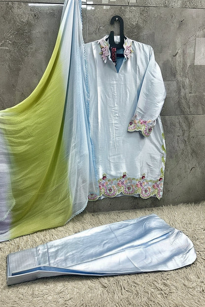 A light blue traditional women's outfit set hanging against a textured gray wall, including a kurta with floral embroidery, matching pants, and a gradient dupatta in yellow-green and light blue. The text 'HF-865' is visible in the bottom right corner.