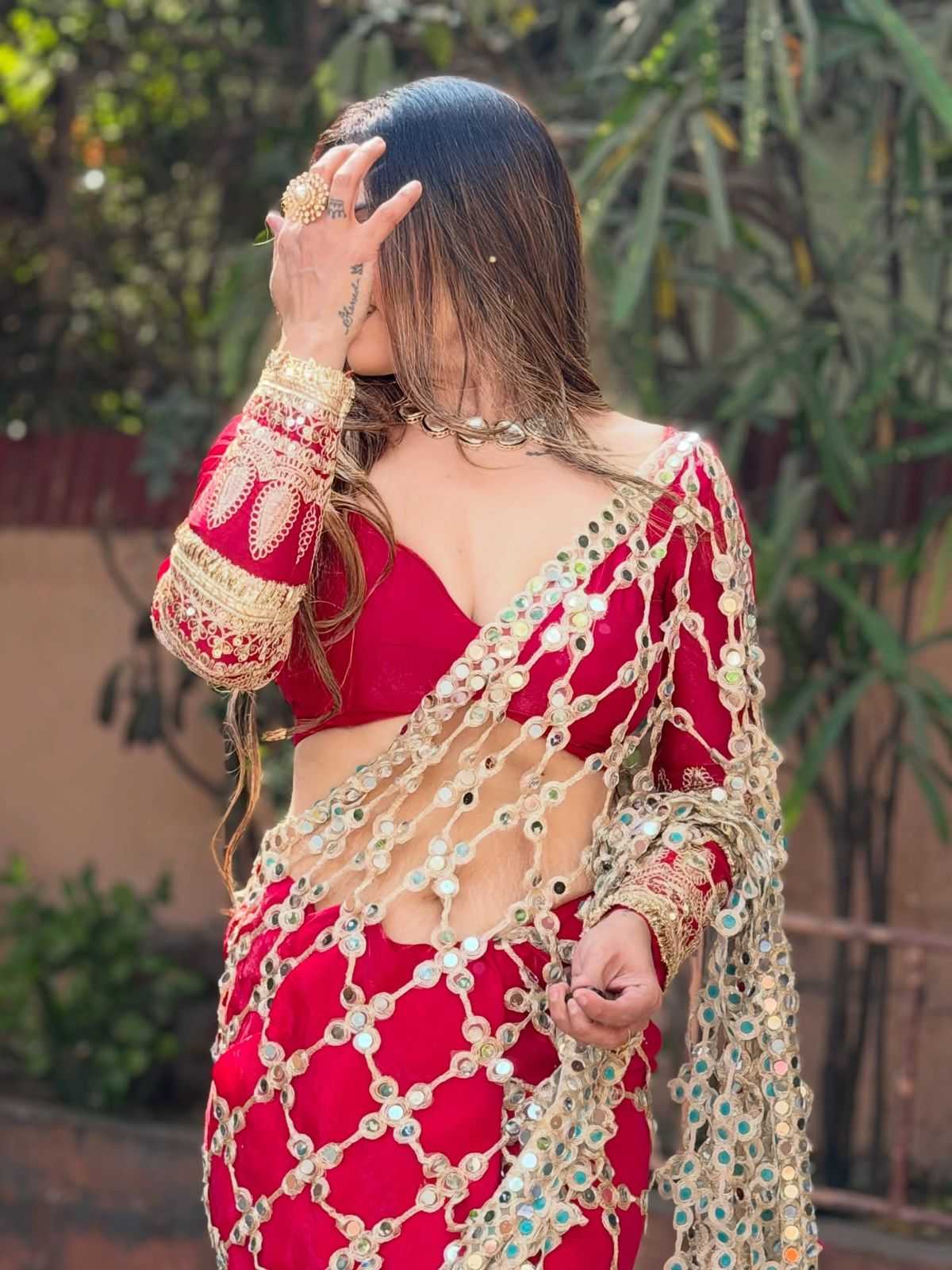 Woman wearing a red and gold traditional outfit with a blurred green background