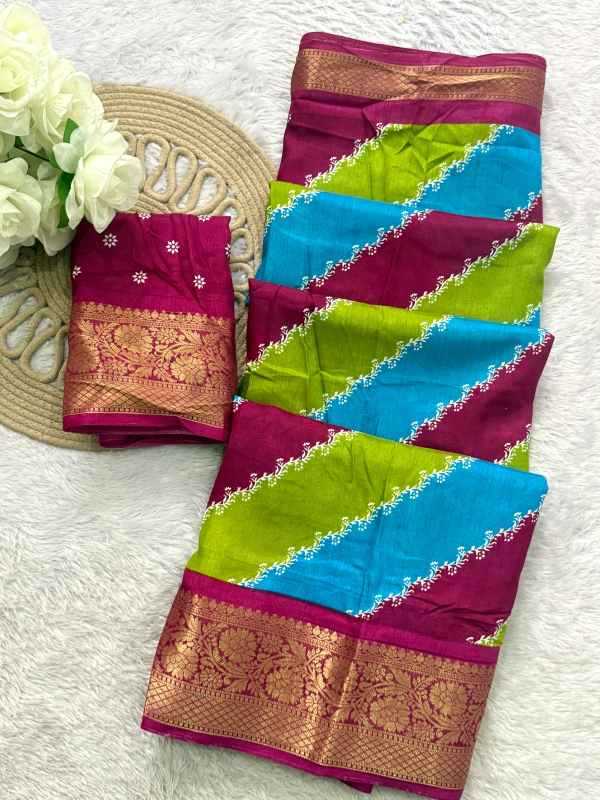 A folded multicolor saree displayed on a white textured surface, featuring diagonal stripes of magenta, turquoise blue, and lime green with gold zari borders and white floral embroidery. A matching small fabric swatch is placed on the left next to white flowers and a woven mat.