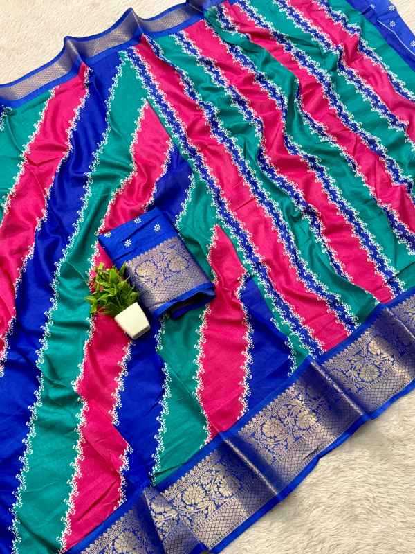 A vibrant striped saree fabric with diagonal bands of teal green, hot pink, and royal blue, featuring intricate silver zari embroidery and a wide metallic border. A matching blue and silver embroidered blouse piece is folded and placed on top of the saree, with a small potted plant prop.