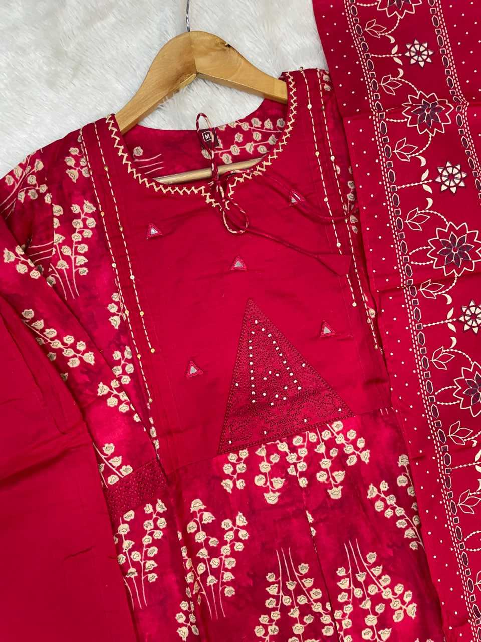 Red traditional outfit with white embroidery on a hanger against a white background