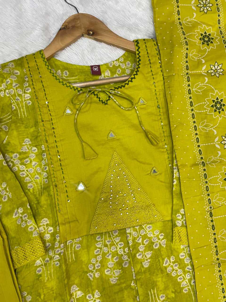 Green embroidered traditional outfit on a hanger with a white background