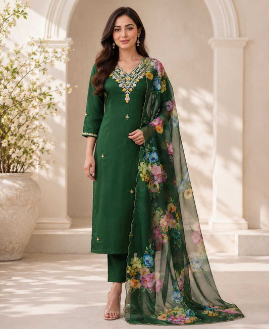 Woman wearing a green traditional outfit with a floral dupatta in an outdoor setting.