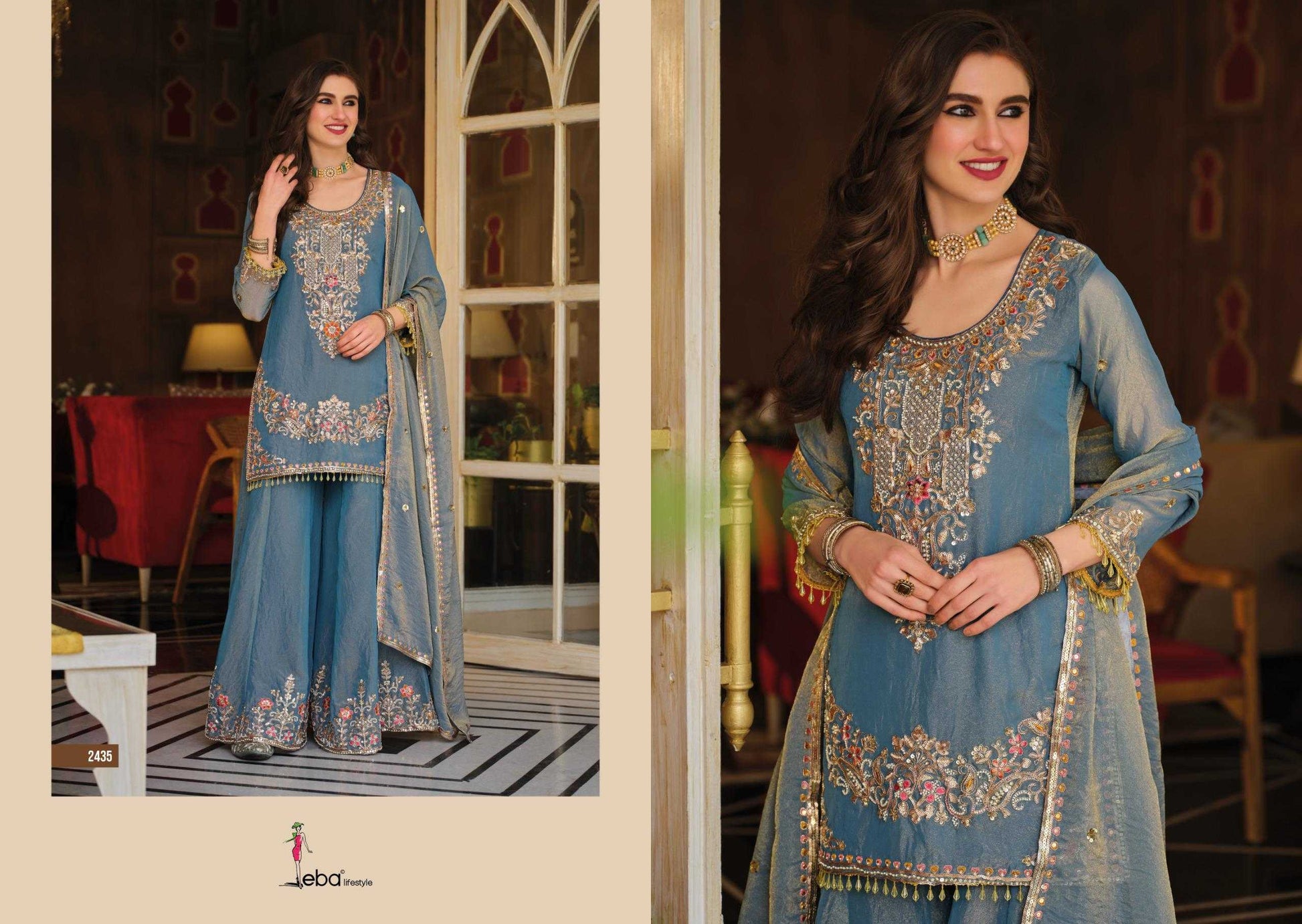 Woman in a blue embroidered traditional outfit standing in a decorated room.