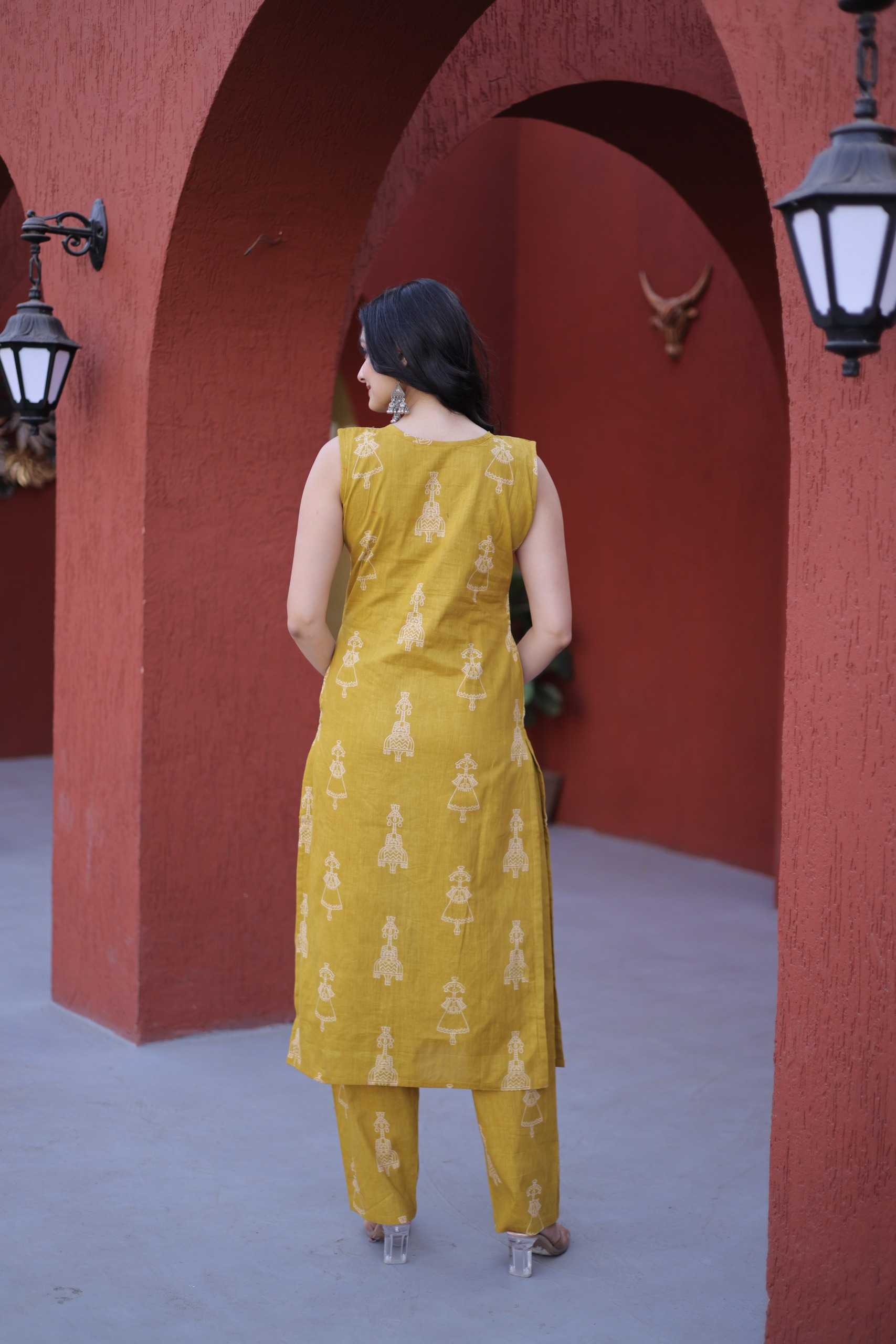 Woman in a yellow dress standing in an archway with red walls and a gray floor.