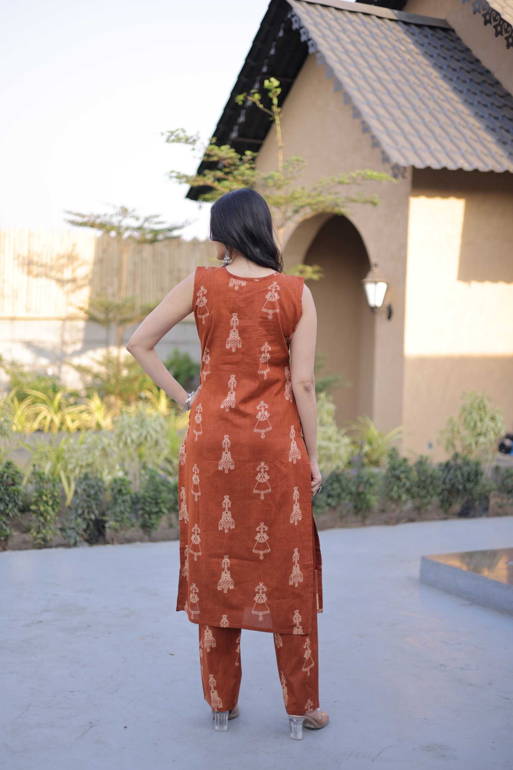 Woman wearing an orange traditional outfit with a pattern, standing outdoors.